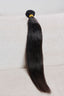 Single bundle of black hair extensions on a white surface